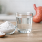 베이킹 소다가 담긴 그릇과 물컵이 주방 테이블 위에 놓여 있어 베이킹 소다와 위장 반응의 관계를 시각적으로 표현한 이미지